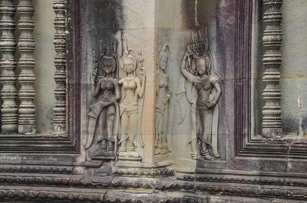Carved bas-reliefs Devatas on facade and wall of Angkor Wat. Angkor - UNESCO World Heritage site. Cambodia, Siem Reap