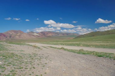 Moğol Altai 'si. Dağ geçidi. Toprak yol. Manzaralı vadi ve çok renkli dağlar. Doğa ve seyahat. Moğolistan, Bayan Olgii Eyaleti