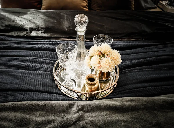 Luxurious bottle and glass set on the bed.