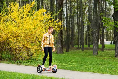 Altın ceket etkin kız rides bakiyeleri kendini scooter Dengeleme üzerinde