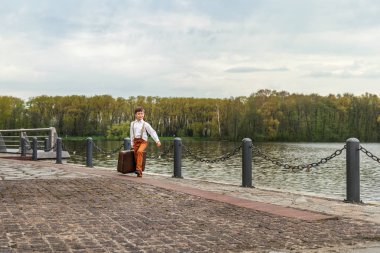 rustik çocuk iskelenin büyük bir retro eski çanta ile yürüyor