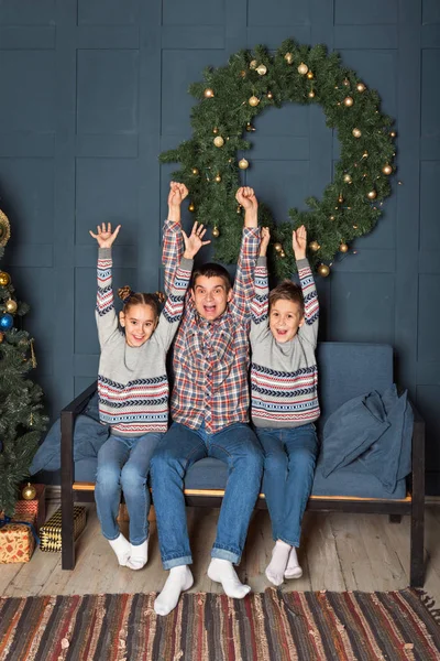 cheerful screaming bouncing family on the couch out of dad and sibling children throwing up their hands