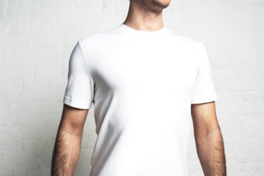 Genç atletik erkek beyaz boş t-shirt, yatay stüdyo yakın çekim, boş duvar