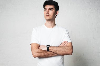 Ciddi genç atletik giyen boş beyaz t-shirt, adam boş duvar, yatay stüdyo portre 