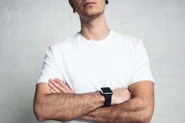Boş beyaz t-shirt ve akıllı izlemek, boş duvar, yatay stüdyo yakın çekim giyen genç atletik adam