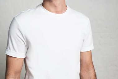 Genç adam beyaz boş t-shirt, yatay stüdyo yakın çekim, boş duvar
