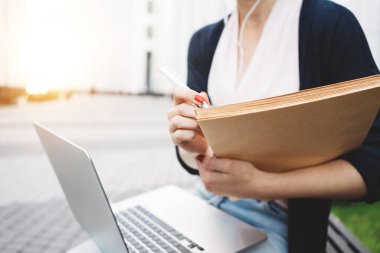 Öğle yemeği sırasında iş iş kadın kullanımı modern dizüstü ve kağıt belgeleri break. Genç kız öğrenci için bir tez açık havada kentsel alanda oturur hazırlar Üniversitesi karşısında. Parlama Efekti