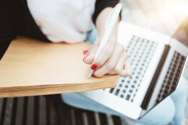 Kentsel alanda açık havada sınavlara hazırlanırken kız öğrenci üzerinde yakından görmek dizüstü bilgisayarı kullanıyor ve kağıt belgeleri. Kağıt üzerinde iş kadın yazar 