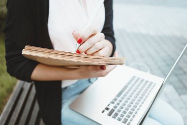 Öğle yemeği sırasında iş iş kadın kullanımı modern dizüstü ve kağıt belgeleri break. Genç kız öğrenci için bir tez açık havada kentsel alanda oturur hazırlar Üniversitesi karşısında