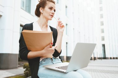 Düşünceli kız öğrencinin Üniversite Parkı oturur ve sınavları için hazırlar. Genç öğretmen ders ve bilgi Internet üzerinde arar kentsel sokakta oturan bir dizüstü bilgisayar ile hazırlar