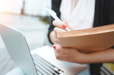 Genç kız öğrenci için bir tez açık havada kentsel alanda oturur hazırlar Üniversitesi karşısında. Modern dizüstü ve kağıt belgeleri biraz mola öğle yemeği sırasında iş iş kadın