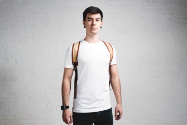 Şık genç adam beyaz boş t-shirt ve sırt çantası, yatay stüdyo portre