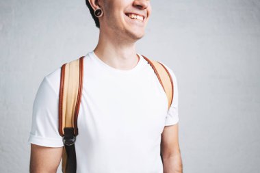 Beyaz boş t-shirt ve sırt çantası, yatay stüdyo portre, boş duvar şık gülümseyen adam görmek