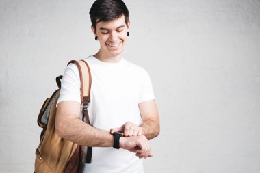 Genç adam giyen beyaz tişört ve packpack, stüdyo portre gülümseyen