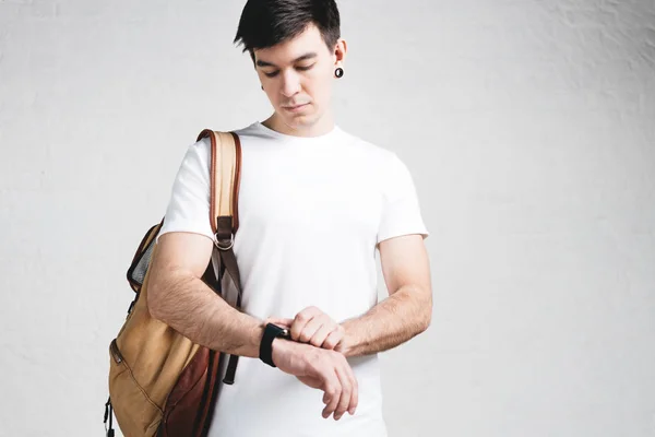 Młody Facet Sobie Pustej Biały Shirt Plecak Smartwatch Puste Ściany — Zdjęcie stockowe