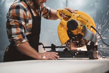 Metal işleme fabrikasında elektrik Köşeli taşlama makinesi kullanarak çalışan makinist sakallı. Eylem iş. Ayrı kıvılcımlar. Yatay