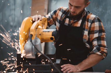 Sakallı güçlü mekanik elektrik Köşeli taşlama makinesi fabrikasında, kıvılcım sinek ayrı kullanarak. Metal işleme tesisi sürecinde iş. Yatay