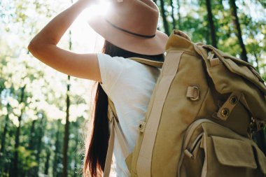 Sırt çantası ve yalnız ormandaki ağaçlar arasında üzerinde açık havada yolculuk şapka giyen cesur hipster kadın