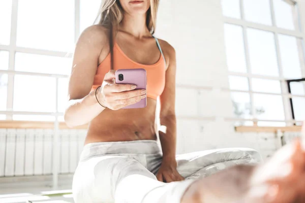Mujer Deportiva Sentada Esterilla Yoga Soleado Gimnasio Blanco Con Teléfono — Foto de Stock