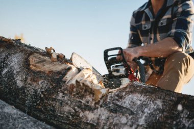 Güçlü oduncu ekose gömlek ve şapka kullanmak chainsaw kereste fabrikası içinde giyen görünümü kapatın. Talaş sinek apart
