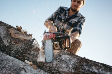 Güçlü oduncu giyen ekose gömlek ve şapka chainsaw kereste kullanın. Talaş sinek apart