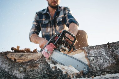 Yel değirmeninin kola üzerinde çalışmak için Chainsaw kullanma ekose gömlek giymiş profesyonel oduncu wprker sakallı. Talaş sinek apart
