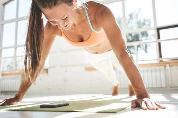 Deportiva Mujer Fuerte Haciendo Flexiones Estera Fitness Mira Teléfono Inteligente — Foto de Stock