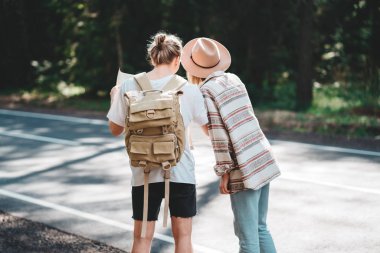 Eller merkezinin haritası ve ormandaki ağaçlar arasında arama yönlü yolcuları hipsters kadın ve erkek sırt çantası ile tutun