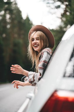 Boho tarzı kadın büyük mesafe içine bir araba ve bir görünüm direksiyonun başında oturuyor. Güzel kız hipster orman yolu zevk