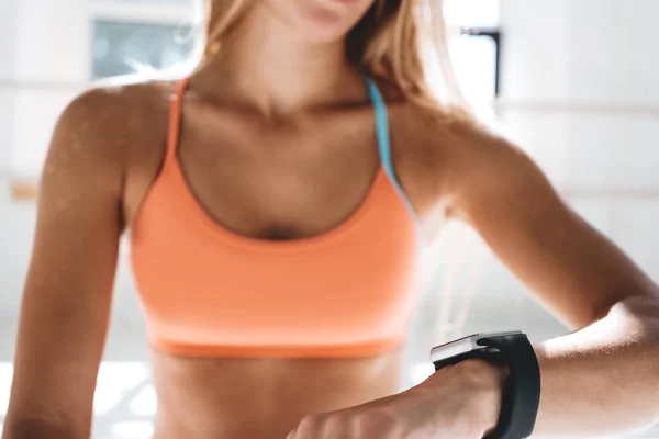 Photo fit woman after workout session checks results on smartwatch in fitness app