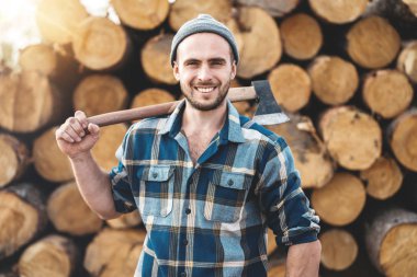 Güçlü ekose gömlek tutar balta onun omuz kereste fabrikası arka plan üzerinde giyen oduncu sakallı