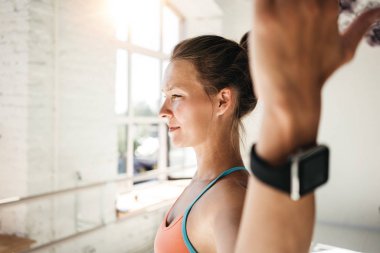 Yanık tenli kadın kapalı spor salonu kolundaki akıllı seyretmek yakından görmek. Arka plan bulanık. Spor kadın fitness egzersiz yapıyor akıllı saati