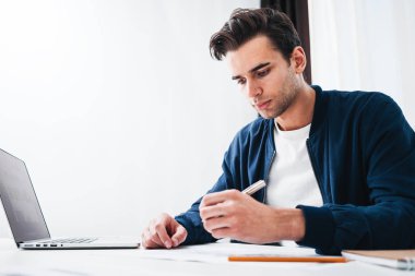 Genç tasarımcı çalışma modern loft Studio dizüstü bilgisayarda çalışırken masada oturan adam. Not defteri ve compute kullanarak office Manager'da portresi