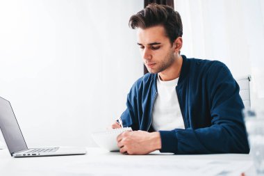 Çekici bir adam alan ofis oturma tablo sırasında dizüstü bilgisayarda çalışıyor. Not defteri çalışma raporu yazma işadamı