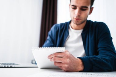 Çekici işadamı masada otururken dizüstü ve Not defteri ofisinde çalışıyor. Genç adam analiz bilgisayar ekranında dijital raporları