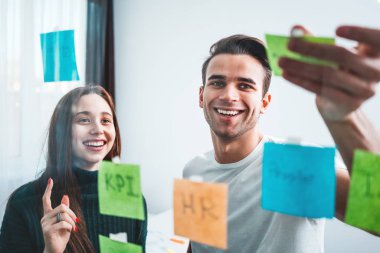 İş stratejisi hazırlamak ve bir yapışkan cam Not duvara yayınlanan akıllı coworking insanlar. Yeni iş fikirleri üzerinde beyin fırtınası gülümseyen Yöneticisi takım 