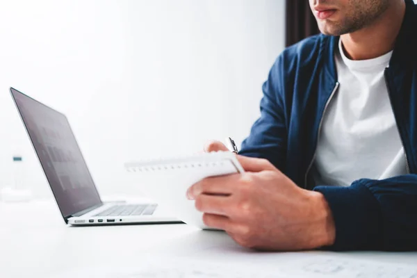 Hombre Concentrado Escribiendo Nuevas Ideas Bloc Notas Mirando Computadora Portátil — Foto de Stock