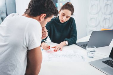 Birlikte modern ofiste çalışan ve dizüstü bilgisayar kullanarak iki iş arkadaşları. Masada oturan ve yeni büyük fikirler hakkında toplantı olan genç coworking insanlar takım