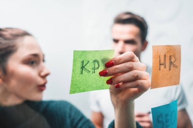 Ofis alanının yapışkan notlar ile cam duvarın arkasında ayakta birlikte çalışan insanlar portresi. Takım Yöneticisi disscusing ve yeni sturtup beyin fırtınaları
