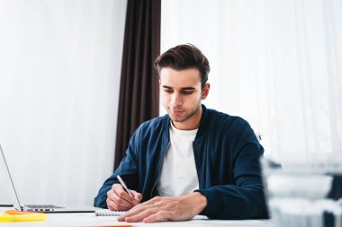 Tablo kullanmak laptop ve ofis alanı Not Defteri'nde oturan işadamı portresi. Genç erkek öğrenci hazırlama projesi