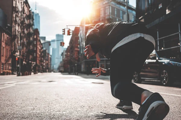 Athlete man in running start pose on urban street. Male runner preparing to run straight through Manhattan streets