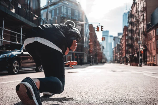 Back view on urban runner in start pose on city street. Prepearing marathon , healthy run concept