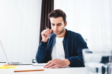 Ofiste çalışan ve laptop ve Not Defteri'ni kullanarak genç yakışıklı bir işadamı. Proje Yöneticisi hazırlama iş planı