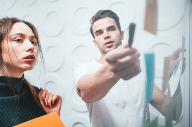 Office Studio yapışkan notlar ile cam duvarın arkasında duran akıllı genç grup insanlar. Takım Yöneticisi disscusing ve yeni sturtup beyin fırtınaları