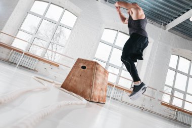 CrossFit egzersiz spor salonunda yapıyor adam uygun. Güçlü atlet kutusunu ışık salonunda atlama
