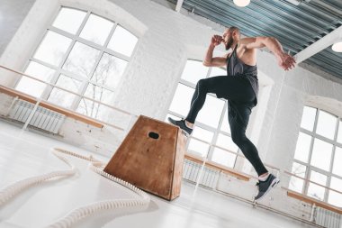 Fitness erkek atlet spor salonunda kutusu ağız kavgası, atlama. Güçlü adam ışık Hall kutusu atlama egzersiz yaparak