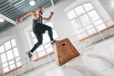 Bir kutu yapan güçlü erkek egzersiz spor salonunda egzersiz atlamak. Crossfit tatbikatların kutusunu kullanarak erkek atlet