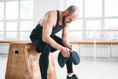 Crossfit spor salonu kutusunda üzerinde oturan yorgun kaslı adam. Güçlü erkek atlet zor egzersiz yaptıktan sonra dinlenme