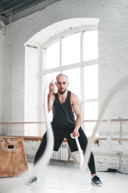 Güçlü adam savaş kullanarak crossfit egzersiz için ipleri. Kaslı erkek atlet spor salonu çapraz savaş halatlar ile çalışma