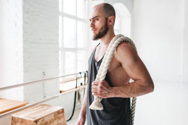 Crossfit halatlar içinde jimnastik salonu ile uygun sporcu görünümü kapatın. Kas atlet savaş tutarak salonu çapraz içinde omuzlarında ipleri